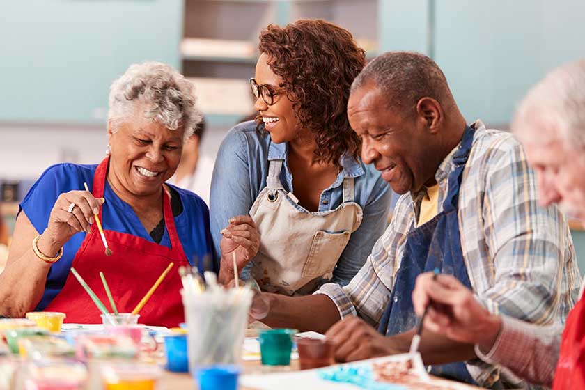 Group Of Retired Seniors Attending Art Class In Community Centre With Teacher