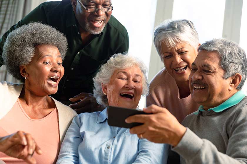 Senior Friends Sitting Sofa Looking Smartphone Retirement