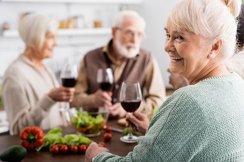 Happy senior woman holding glass of red wine